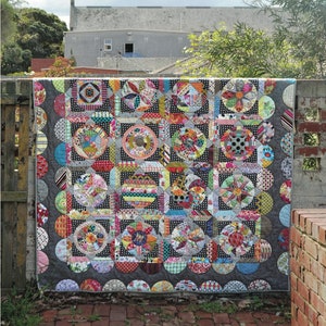 Könnte beinhalten: Ein farbenfroher Quilt mit einem kreisförmigen Muster, betitelt "The Circle Game" von Jen Kingwell.
