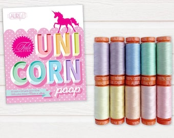 Op de afbeelding: Een set van 10 spoelen pastelkleurige katoenen draad, met het label "Aurifil" en "Made in Italy". De spoelen zijn in een rij op een wit houten oppervlak gerangschikt. De tekst "Unicorn Poop" is zichtbaar op een roze en witte kaart achter de spoelen.