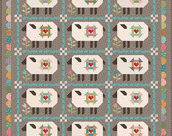 May include: A patchwork quilt with a repeating pattern of sheep motifs, each with a heart design. The sheep are white with black features, set on a grey background with blue and floral details. The quilt has a scalloped edge.
