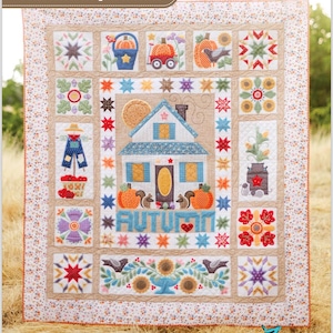 May include: A patchwork quilt with an autumn theme. The quilt features a central house design with pumpkins, squirrels, and the word "AUTUMN". Surrounding the house are various squares with fall-themed images, including sunflowers, birds, and stars. The quilt is bordered with a floral pattern.