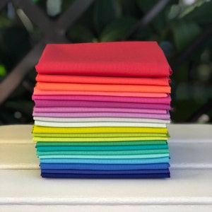 May include: A stack of 15 fabric squares in a rainbow color gradient, starting with red and ending with dark blue.