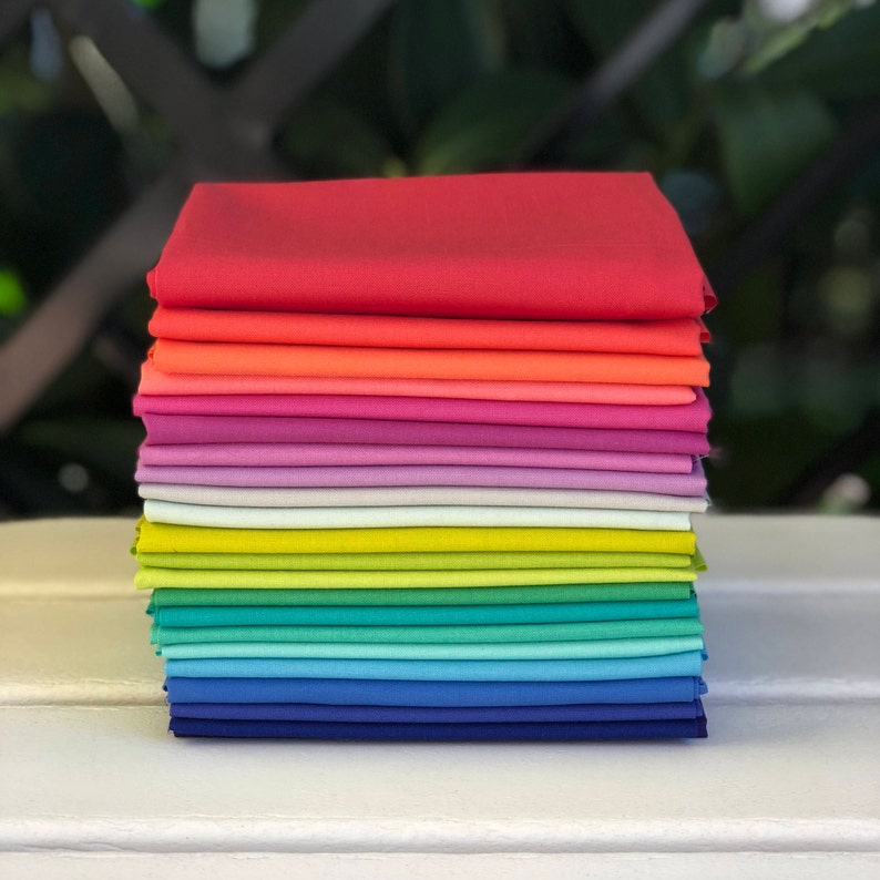 May include: A stack of 15 fabric squares in a rainbow color gradient, starting with red and ending with dark blue.