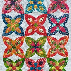 May include: A quilt with a patchwork design featuring nine colorful flower-shaped blocks. Each block is made up of smaller pieces of fabric in various patterns and colors, including red, blue, green, yellow, and orange.