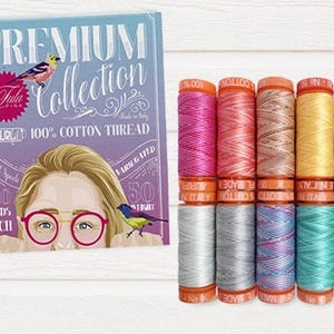 May include: A set of eight spools of 100% cotton thread in various pastel colors. The thread is made in Italy and is part of the "Premium Collection" by Aurifil.