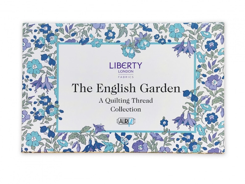 Op de afbeelding: Een witte doos met een blauwe en witte bloemenrand. De doos heeft de tekst "LIBERTY LONDON FABRICS" en "The English Garden A Quilting Thread Collection" met het Aurifil-logo.