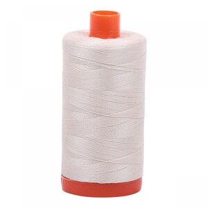 May include: A spool of off-white thread with an orange top and base. The thread is tightly wound around the spool, creating a cylindrical shape. The thread appears to be a light, neutral color, suitable for various sewing projects.