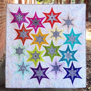 May include: A white quilt with a colorful star pattern. The stars are made of different fabrics and have a variety of colors, including red, orange, yellow, green, blue, purple, and pink. The stars are arranged in a circular pattern, with the largest star in the center.
