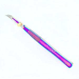 May include: A rainbow-colored, stainless steel craft knife with a gold knob and the text "Lila Pink" on the handle.
