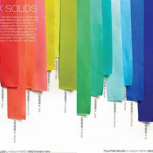 May include: A collection of fabric swatches in various shades of pink, orange, yellow, green, blue, and white. The fabric swatches are labeled with the color name and a code. The text "Tula Pink Solids" is at the top of the image.