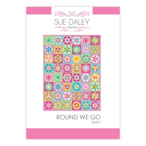May include: A quilt pattern by Sue Daley Designs, titled "Round We Go". The quilt design features a grid of colourful, circular patterns with star and geometric shapes in shades of pink, blue, yellow, and green. The background is white with pink borders.