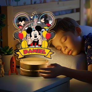 May include: A Mickey Mouse-themed night light with the name "DANIEL" displayed on a banner. The lamp features a cartoon image of Mickey Mouse, balloons, and a castle. The base is made of wood.