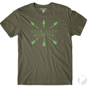 May include: A green t-shirt with a white graphic design that says "Star City Archery Club". The graphic features a star with five arrows pointing towards the centre.