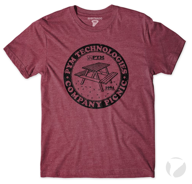 K&ouml;nnte beinhalten: Ein maronfarbenes T-Shirt mit einem schwarzen Kreis-Motiv, das einen Picknicktisch und den Text "PYM TECHNOLOGIES COMPANY PICNIC 1984 SAN FRANCISCO" zeigt.