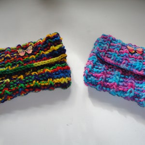 May include: Two crocheted clutches with butterfly embellishments. One clutch is a rainbow of colors, the other is a mix of pink and blue.