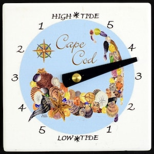 May include: A white ceramic tide clock with a blue face and a black pointer. The face features a map of Cape Cod made of seashells and the words "High Tide" and "Low Tide".