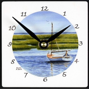 May include: A white ceramic clock with a blue, green, and white sailboat scene. The clock face has black hands and black Roman numeral markings. The clock face is surrounded by a white border with black numbers 1 through 12.