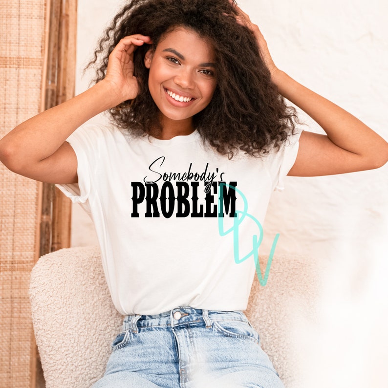 May include: A white t-shirt with black text that reads "Somebody's PROBLEM" in a bold, cursive font.