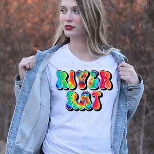 May include: A white t-shirt with a tie-dye design of the words "River Rat" in a retro font.
