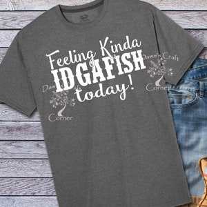 May include: A heather gray t-shirt with the text "Feeling Kinda IDGAFISH today!" in white. The text is surrounded by a stylized tree design with the words "Dawn's Craft Corner" on either side.