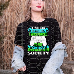 Puede incluir: Una camiseta negra con un gr&aacute;fico verde y blanco de un mando de videojuego. El texto en el gr&aacute;fico dice "Si puedes leer esto, me vi obligado a dejar mi mando y volver a entrar en la sociedad."