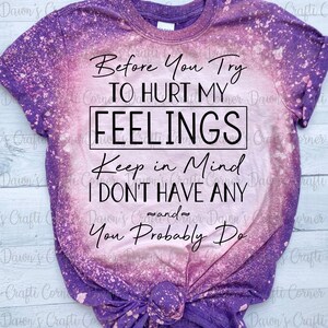 K&ouml;nnte beinhalten: Ein lila- und rosafarbenes Batik-T-Shirt mit dem Text "Before You Try To Hurt My Feelings Keep In Mind I Don't Have Any And You Probably Do" in Schwarz.