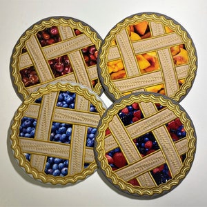 May include: Four decorative pie crusts with different fruit fillings. The crusts are gold with a woven pattern and the fillings are cherries, blueberries, peaches, and raspberries.