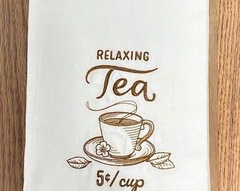 May include: White kitchen towel with brown embroidery of a teacup and teapot with the text "Relaxing Tea 5¢/cup"