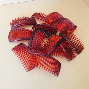 May include: A pile of ten brown plastic hair combs. The combs are all the same size and shape, and they are arranged in a random pattern.
