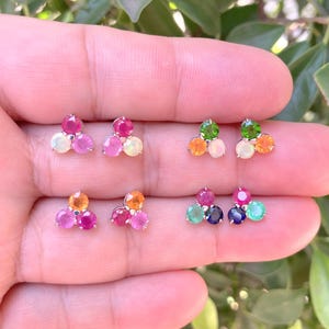 May include: Three pairs of earrings, each with three gemstones. The earrings are silver and feature a variety of colours, including pink, green, blue, orange, and white.