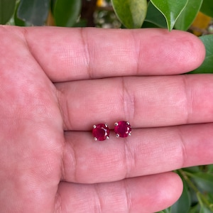 Könnte beinhalten: Ein Paar silberne Ohrstecker mit runden, roten Edelsteinen.