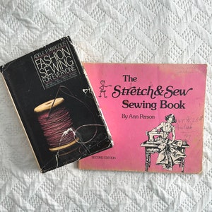 May include: Two vintage sewing books. The first book is black with a spool of thread on the cover and the title "Fashion Sewing for Everyone". The second book is pink with a drawing of a woman sewing on a sewing machine and the title "The Stretch & Sew Sewing Book" by Ann Person.