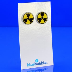 May include: A pair of yellow and black radiation symbol earrings. The earrings are on a white card with the text "bluebubble."