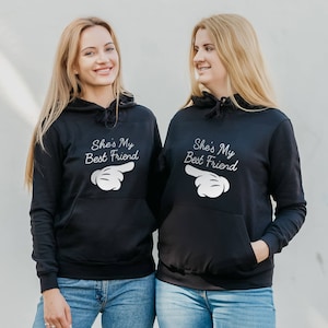 Two women with matching printed hoodies - hoodies with print phrase she is my best friend - herringbone neck tape hoodie - kangaroo pocket, side seams, brushed inside, elastic cuffs and waistband hoodies - black bff matching hoodies - bestie hoodies