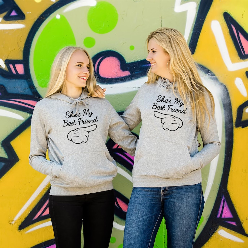 Two women with matching printed hoodies - hoodies with print phrase she is my best friend - herringbone neck tape hoodie - kangaroo pocket, side seams, brushed inside, elastic cuffs and waistband hoodies - grey bff matching hoodies - bestie hoodies