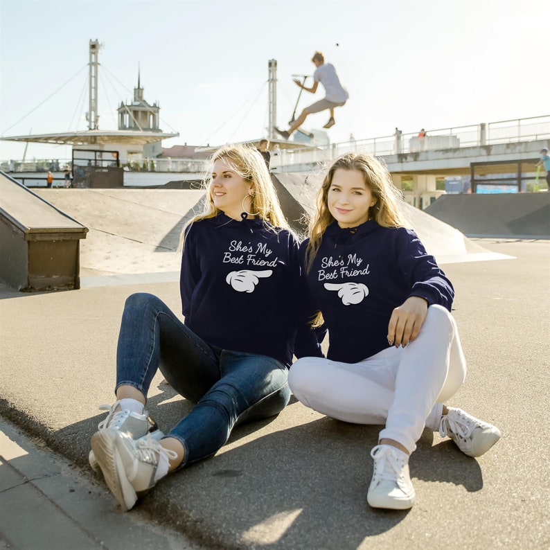 Two women with matching printed hoodies - hoodies with print phrase she is my best friend - herringbone neck tape hoodie - kangaroo pocket, side seams, brushed inside, elastic cuffs and waistband hoodies - blue bff matching hoodies - bestie hoodies