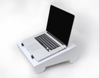 Op de afbeelding: Een witte laptopstandaard met een laptop erop. De laptop is zilverkleurig en heeft een zwart scherm. De standaard is schuin en heeft afgeronde randen.