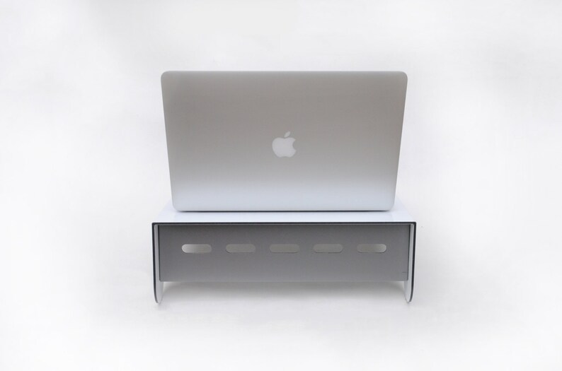 May include: A white laptop stand with a silver laptop on top. The stand has a series of small holes in the front.