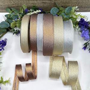 May include: Five spools of metallic ribbon in gold, silver, and copper colors. The ribbon has a textured, glittery finish and is perfect for adding a touch of sparkle to crafts, gifts, and home decor.