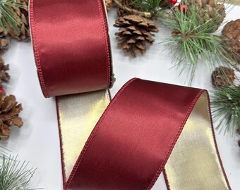 Op de afbeelding: Een breed, dubbelzijdig lint met een diepe bordeauxrode satijnen afwerking aan de ene kant en een metallic gouden afwerking aan de achterkant. Het lint is in een vloeiende S-vorm gelegd, waardoor beide zijden duidelijk zichtbaar zijn.