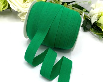 May include: A spool of bright green elastic ribbon. The ribbon is wound around a white spool and is ready to be used for sewing or crafting projects.