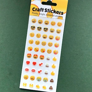 May include: A sheet of craft stickers featuring various emoji designs. The stickers include smiling faces, sunglasses, hearts, and other fun graphics. The packaging reads "Craft Stickers: Funky, bright, colourful stickers."