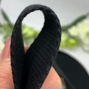 May include: Close-up of black fabric with a soft, fuzzy texture. The fabric is folded in half, showing the inside of the material.