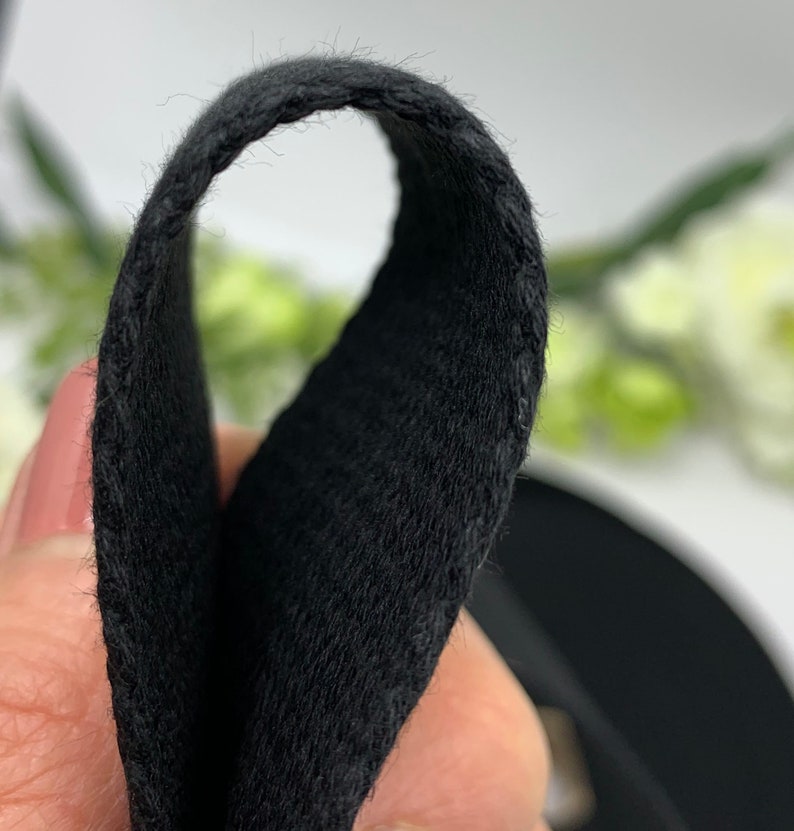 May include: Close-up of black fabric with a soft, fuzzy texture. The fabric is folded in half, showing the inside of the material.