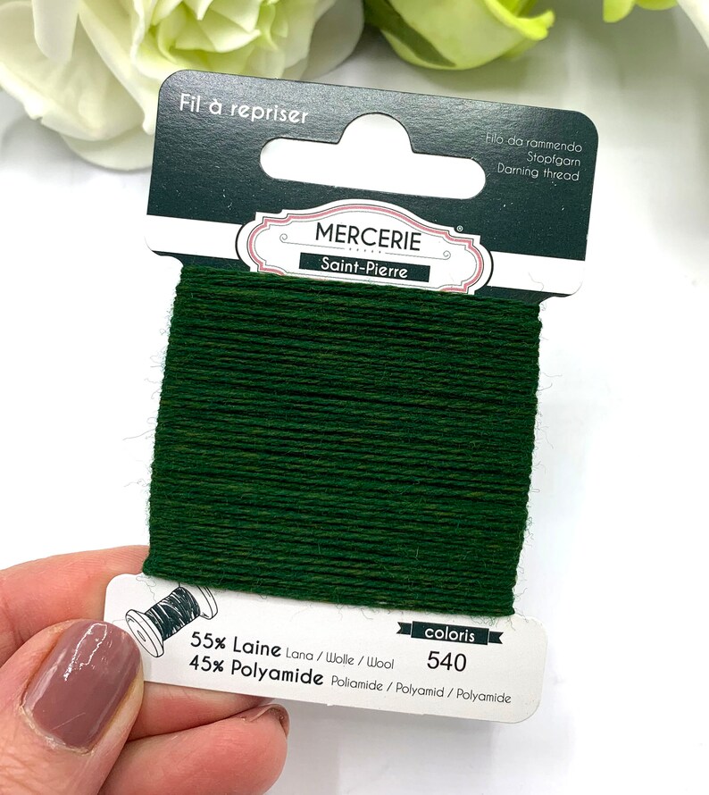 May include: A spool of dark green darning thread labeled "Mercerie Saint-Pierre" with the text "Fil &agrave; repriser" and "coloris 540". The thread is 55% wool and 45% polyamide.