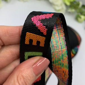 May include: Black woven ribbon with a rainbow pattern and the word "LIFE" in orange, green, and pink lettering.