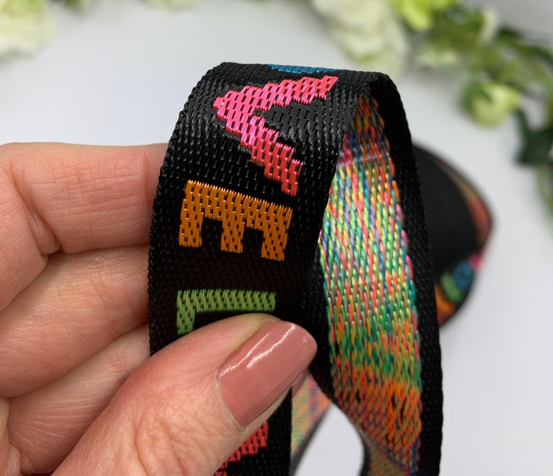 May include: Black woven ribbon with a rainbow pattern and the word "LIFE" in orange, green, and pink lettering.