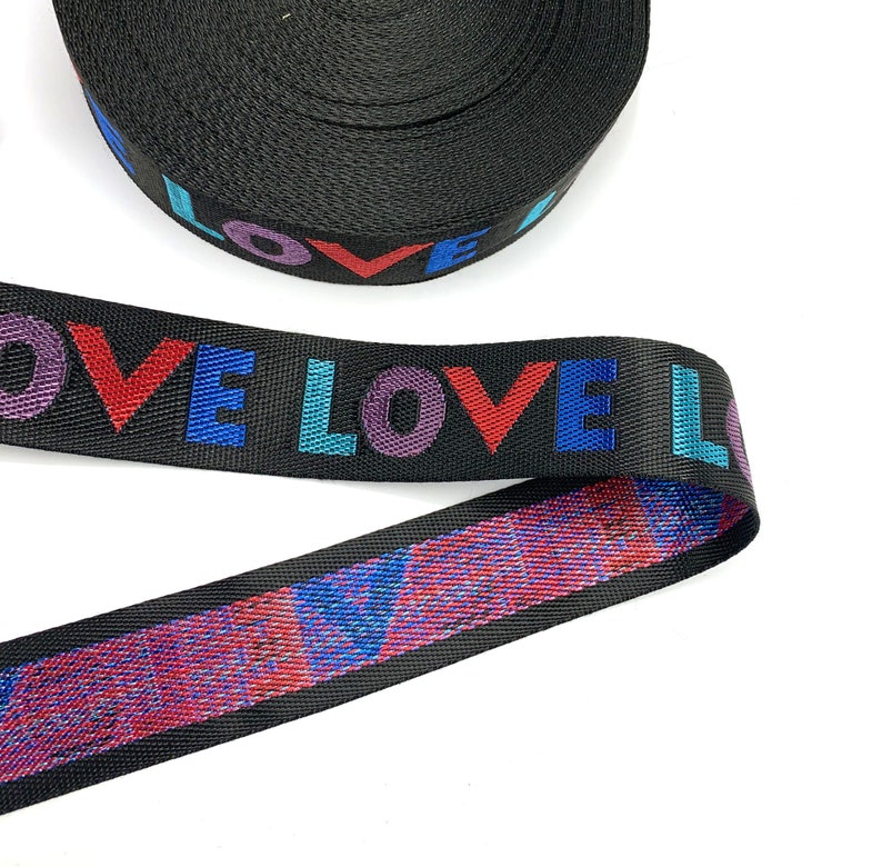 May include: Black webbing with the word "LOVE" printed in rainbow colors. The webbing has a glittery red and blue pattern on the back.