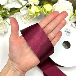 May include: A roll of deep burgundy satin ribbon. The ribbon is 1 inch wide and has a smooth, shiny finish.