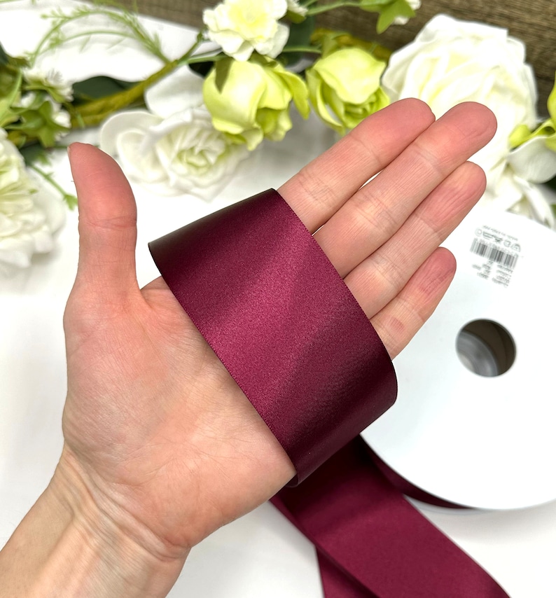 May include: A roll of deep burgundy satin ribbon. The ribbon is 1 inch wide and has a smooth, shiny finish.