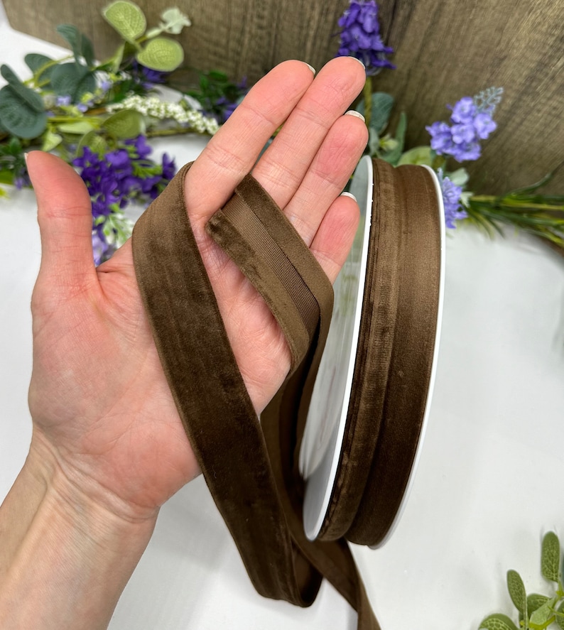 K&ouml;nnte beinhalten: Eine Spule mit braunem Samtband. Das Band ist etwa 2,5 cm breit und hat eine weiche, pl&uuml;schige Textur.